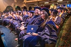 Graduate students pose after receiving their diploma.